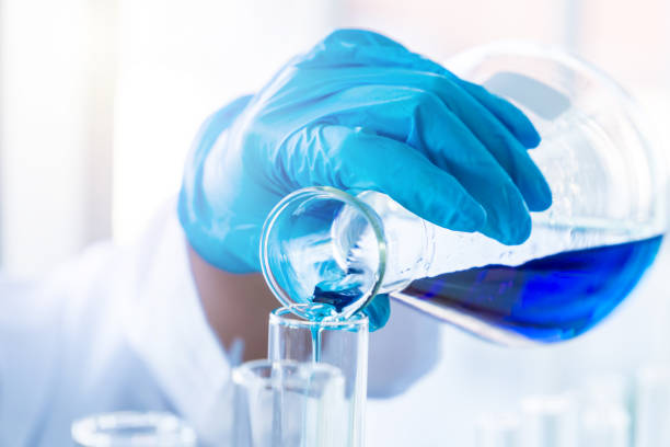 istock Scientist pouring chemical into test tube. 1206219755