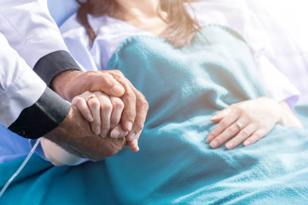 Patient recovery Male doctor holding female patient hand on the hospital bed. bedside manner stock pictures, royalty-free photos & images