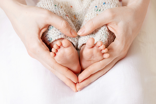 Pies de bebé en las manos de la madre. Pies de bebé recién nacido pequeño en el primer plano de las manos en forma de corazón femenino. Mamá y su hijo. Concepto de familia feliz. Hermosa imagen conceptual de la Maternidad photo