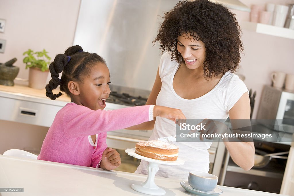 Mother and daughter enjoy icing a cake together Mother and daughter in kitchen icing a cake together smiling Cake Stock Photo