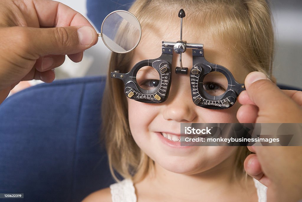 Ottico dando giovane ragazza a un esame oculistico - Foto stock royalty-free di Accudire