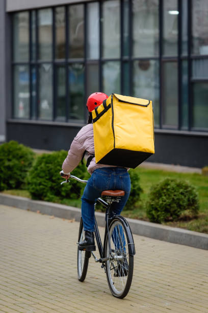 istock Back view of courier with thermo backpack riding bicycle on urban street 1206225404