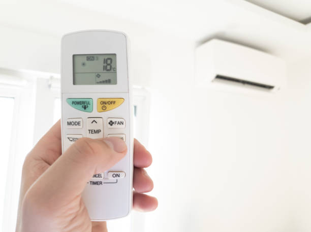 istock Modern air conditioner unit with a hand holding a remote. 1206226225
