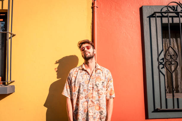 Portrait of a smiling man looking at the camera Horizontal portrait of a handsome man leaning on yellow and red wall cool attitude fashion stock pictures, royalty-free photos & images