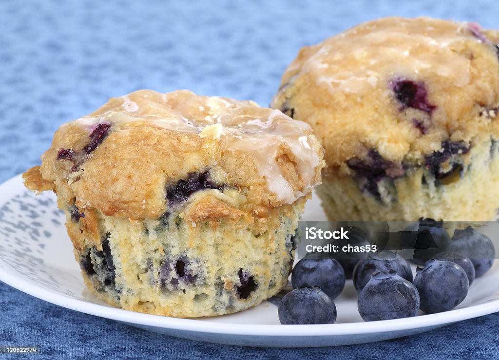 Blueberry Muffins Two blueberry muffins with berries on a plate Blueberry Muffin Stock Photo