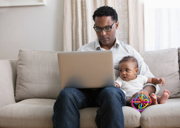 Father working from home and taking care of baby daughter stock photo