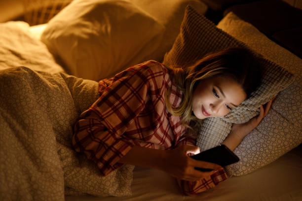istock Beautiful young woman using mobile phone in bed at night 1206233664