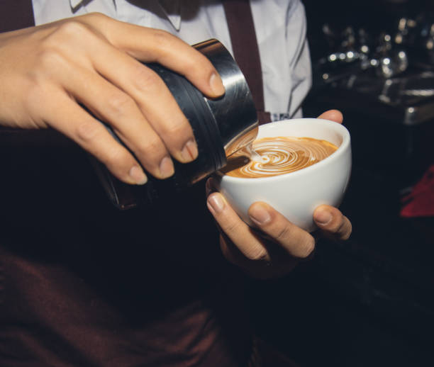 Barista making a cup of coffee latte art in coffee shop