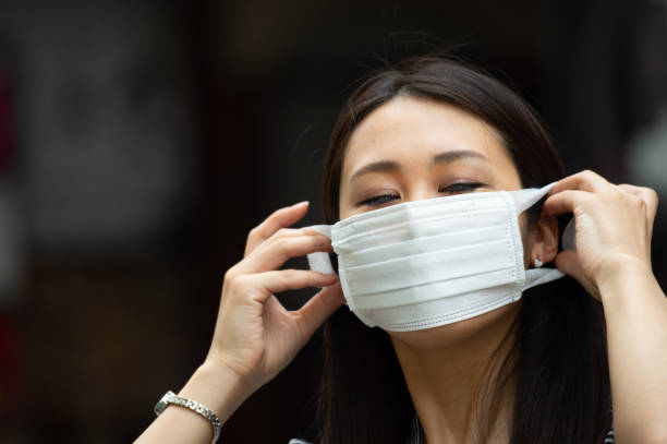 istock Asian woman putting on face mask 1206236033
