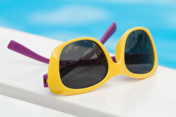 istock Children sunglasses lying on a deck-chair on blue water background 1206238594