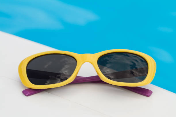 istock Children sunglasses lying on a deck-chair on blue water background 1206238644