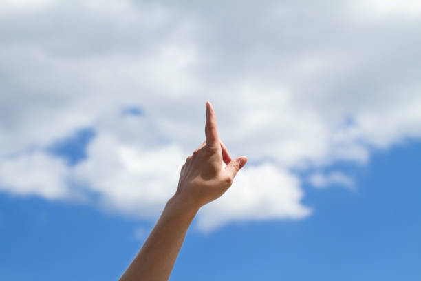 istock Single female hand with one finger pointing towards blue sky 1206238719