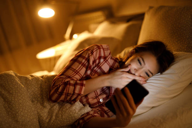 istock Beautiful young woman using mobile phone in bed at night 1206238878