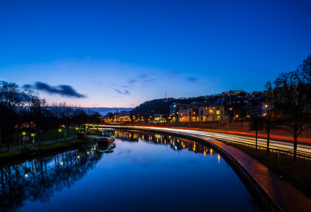 Germany, Saarbruecken city highway traffic and silent water of saar river from night to day sunrise morning stock photo