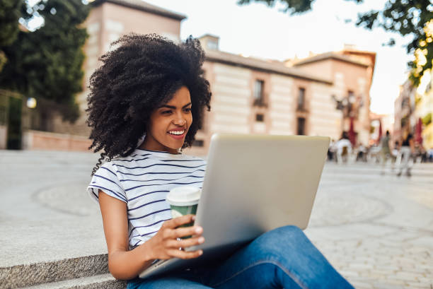istock Cute girl using laptop and drinking coffee on the street 1206243774