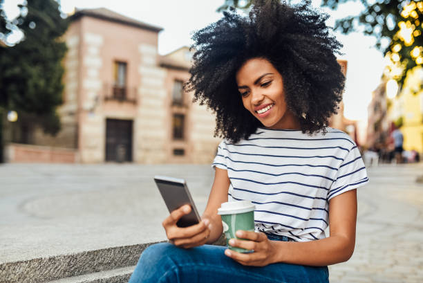 istock Beautiful girl using smartphone and drinking coffee on the street 1206243783