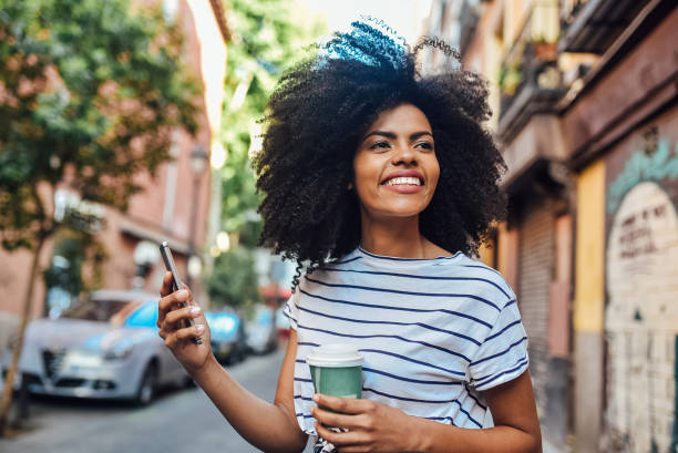 istock Cute Afro girl drinking coffee and using smartphone on the move 1206243790