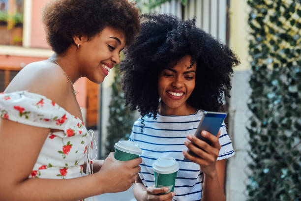 istock Two friends drinking coffee and using a smartphone at the street 1206243900
