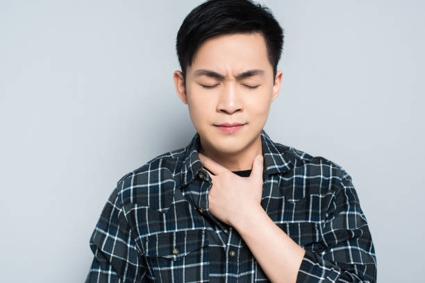 istock young asian man with closed eyes touching neck while suffering from sore throat isolated on grey 1206250481