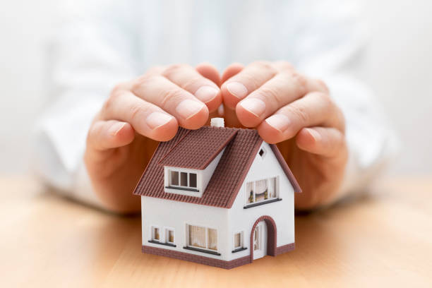 istock Property insurance. House miniature covered by hands 1206250793