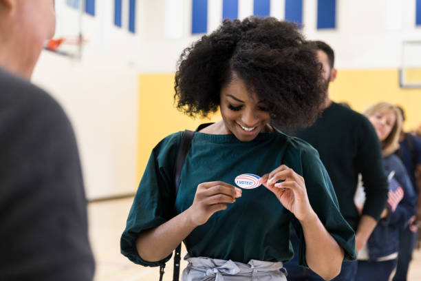 cheerful female voter in polling place - jovens a votar imagens e fotografias de stock