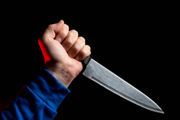 istock A kitchen knife in the man hand is brought in for a strike. Close-up on a black background 1206259971