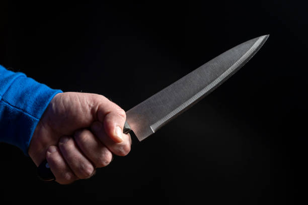 istock Kitchen knife in a man's hand close-up on a black background 1206260006