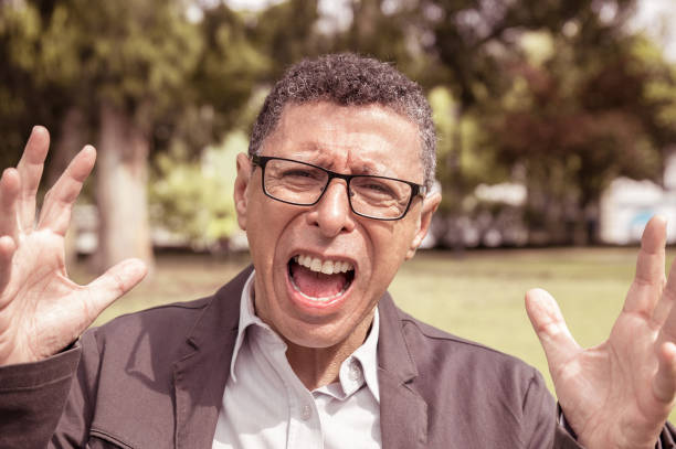 istock Indignant middle-aged man screaming and raising hands in park 1206262175