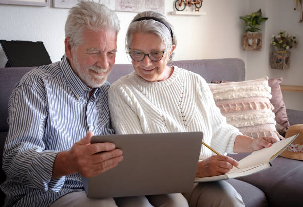 istock A senior couple looks at the laptop with interest and makes a note in a notebook. Plan a trip. White hair. New technology for older people 1206263536