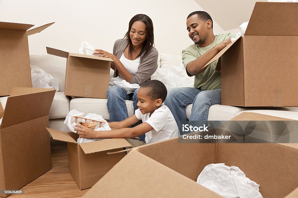 African American Family Unpacking Boxes Moving House African American family, parents and son, unpacking boxes and moving into a new home, The adults are unpacking crockery and houseware, the child is unpacking a toy airplane. Family Stock Photo