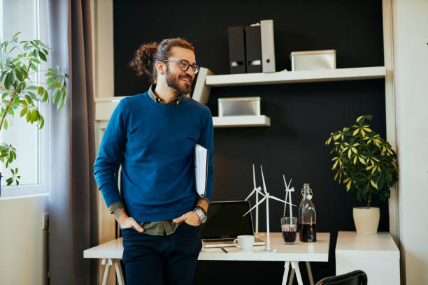 istock Handsome positive young caucasian hipster standing in his office, holding under armpit and preparing to go on meeting with important clients. 1206273616