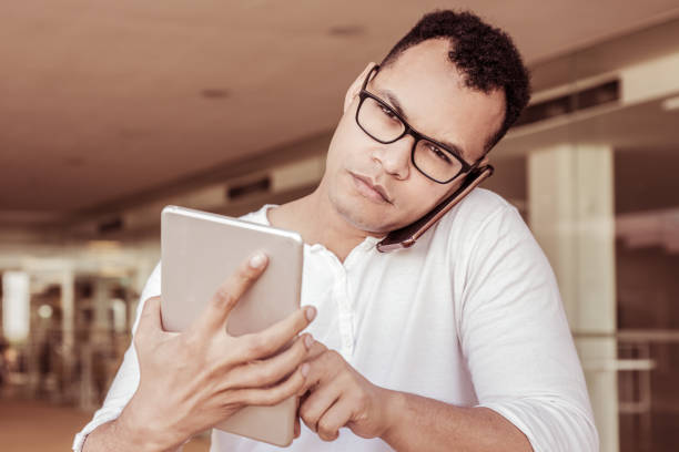 Man working on tablet, talking on phone, looking at camera