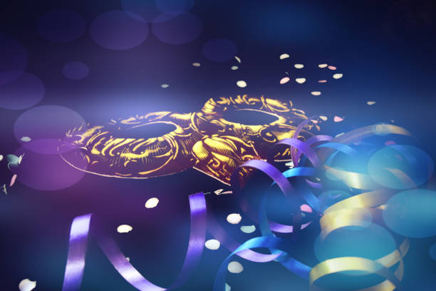 istock one carnival mask on a dark background with a serpentine, confetti with a bokeh effect in blue. Venetian carnival close-up. soft focus 1206280739