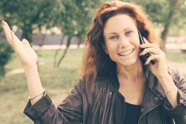 istock Excited lady talking on phone and gesturing in city park 1206283499