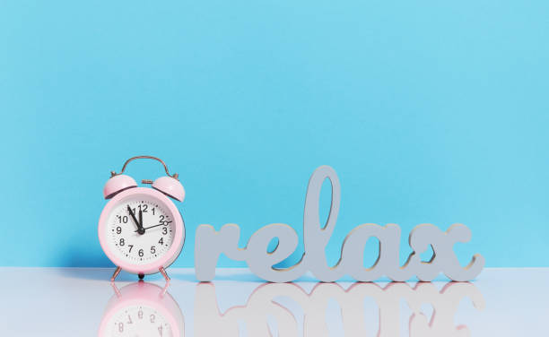 istock Sleep optimization. Relax shape text and a pink alarm clock on a light blue background. 1206285955