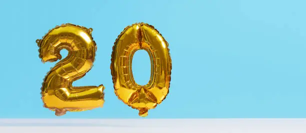 Photo of Golden foil balloon in the shape of numbers on a blue background. Levitation effect