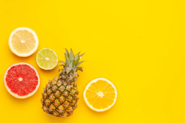 tropical fruits pineapple, orange and lime on yellow background with copyspace - nectarine peach red market imagens e fotografias de stock