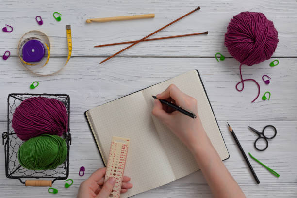 istock Background with knitting and crocheting tools and accessories for starting a project, woman hands writing 1206301144