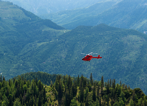 Rescue helicopter flying against high rocky mountain in Julian Alps, Slovenia.