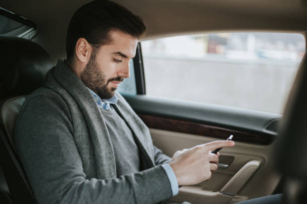istock Businessman is sitting in a back passenger seat and texting 1206304730