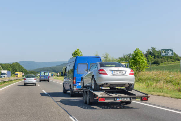 autoträgeranhänger mit auto. blauer kleinbus mit abschleppwagentransporter mit auto auf autobahn - tow truck towing car truck stock-fotos und bilder