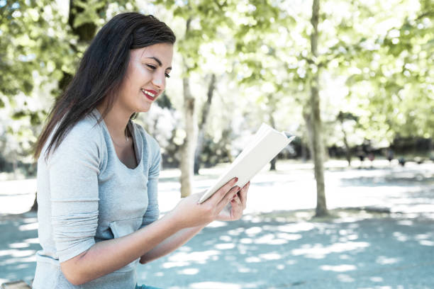 istock Happy pretty young lady reading book in park 1206311304