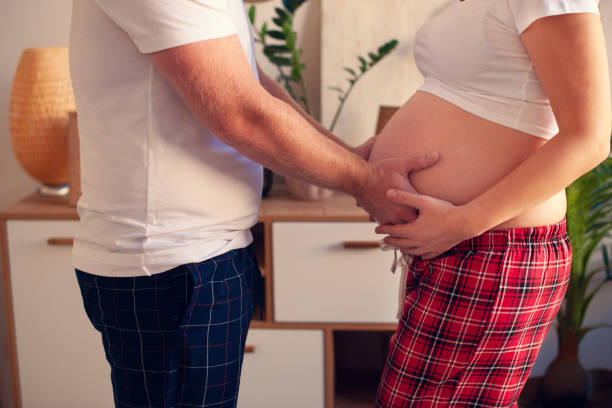 cropped image of beautiful pregnant woman and her handsome husband hugging the tummy - mother exercising baby dieting imagens e fotografias de stock