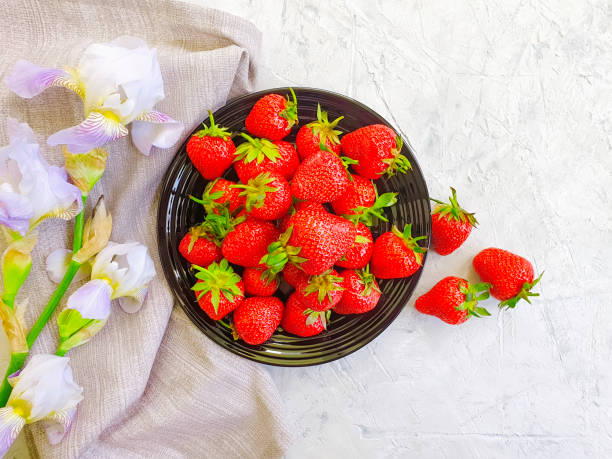 fresh strawberries on a plate on a concrete background flower iris
