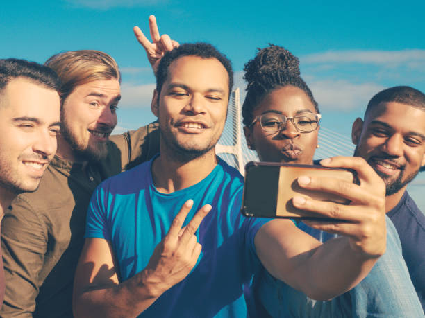istock Smiling friends gesturing while taking self portrait with smartphone. 1206315523