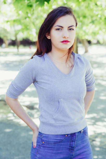 istock Serious pretty young lady standing and posing at camera in park 1206315601