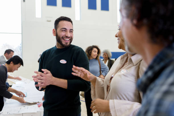 mann lacht mit freunden, während er auf die abstimmung wartet - voting election usa american culture stock-fotos und bilder