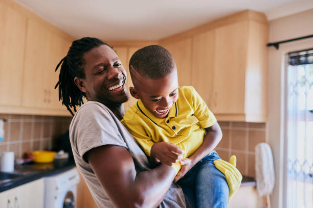 Cleaning time doesn't have to be all boring Cropped shot of an affectionate young single father playing with his son while cleaning in their kitchen at home one parent stock pictures, royalty-free photos & images