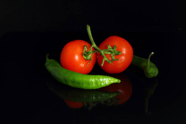 istock isolated peppers and juicy cherry tomatoes. black backgorund. 1206321476