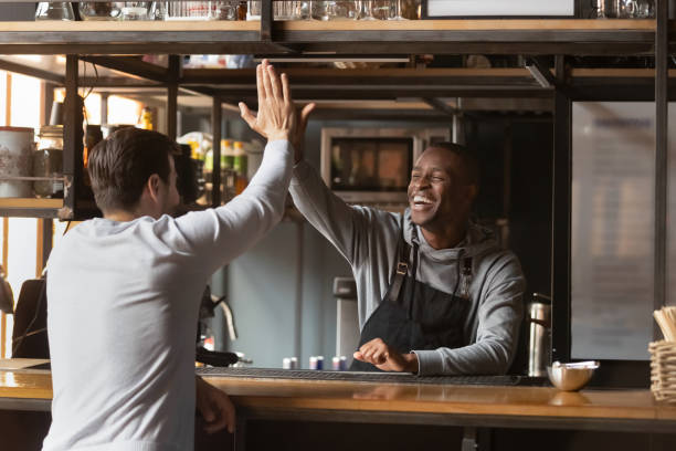 Overjoyed black waiter give high five to male client